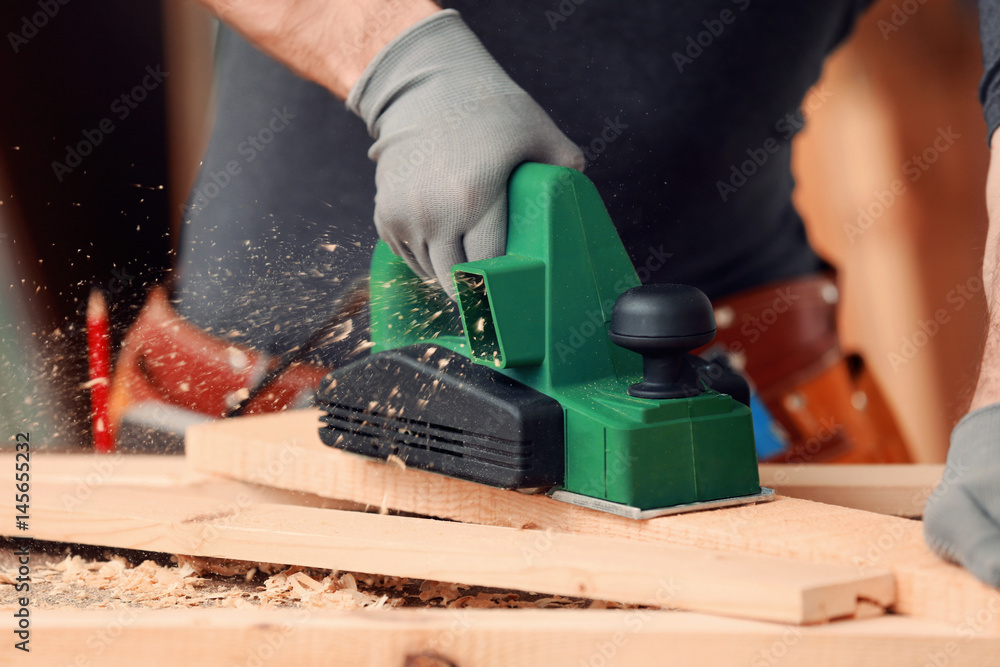 Carpenter with electrical grinder in workshop, closeup Carpenter with electrical grinder in workshop, closeup