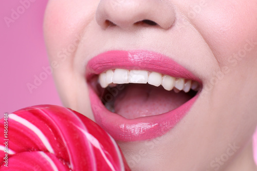 Face of beautiful young woman with lollipop on color background  closeup