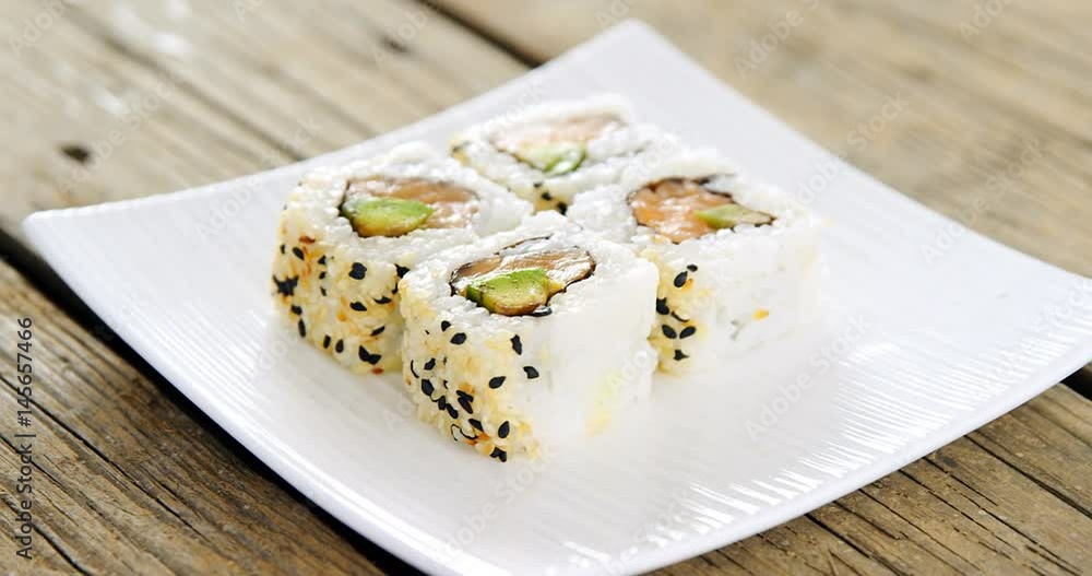 Uramaki sushi served on plate against wooden background Uramaki sushi served on plate against wooden background