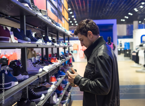 portrait of young male customer choosing sneakers at supermarket store