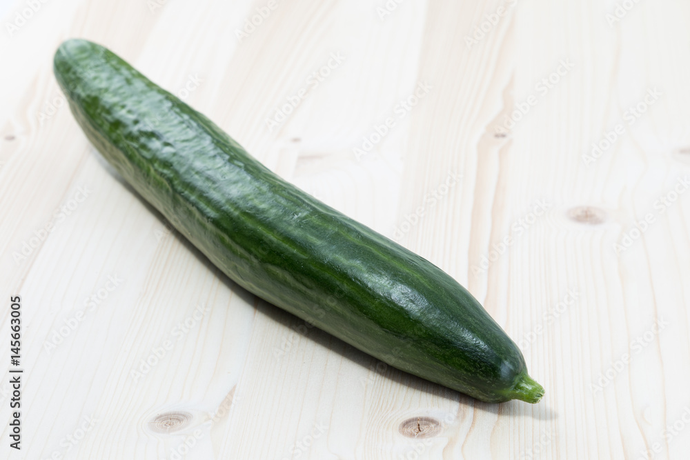 Green cucumber on a pine wood table board Green cucumber on a pine wood table board