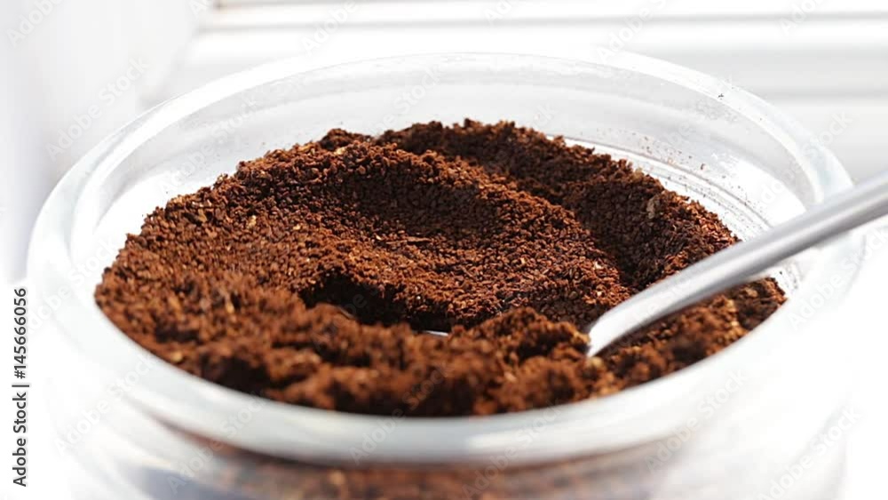 Coffee dosage from a jar with a small spoon on bright white background, macro and close up Coffee dosage from a jar with a small spoon on bright white background, macro and close up