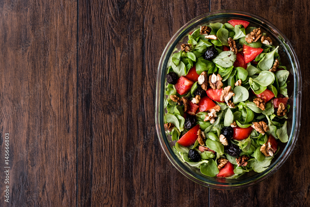 Purslane salad with walnut, tomatoes and olive on wooden surface.