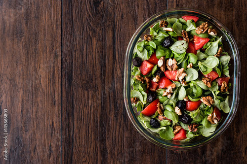 Purslane salad with walnut, tomatoes and olive on wooden surface.