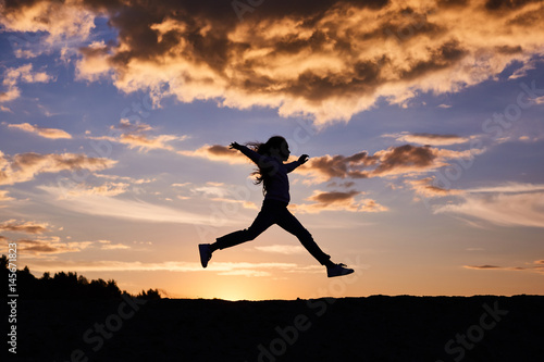 Wallpaper Mural A silhouette of a running girl on sunset sky background Torontodigital.ca