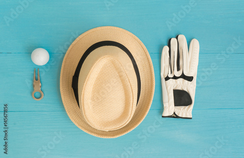 Billede på lærred Golf concept : panama hat, glove, golf balls, divot repair tool on wooden table