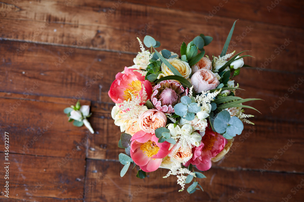 bridal bouquet with peonies and protea and boutonniere on the wooden floor bridal bouquet with peonies and protea and boutonniere on the wooden floor