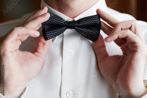man corrects a black bow tie