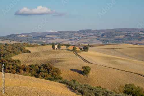 Chapel in the middle of plowed fields in autumn Tuscany with a cloud in the sky