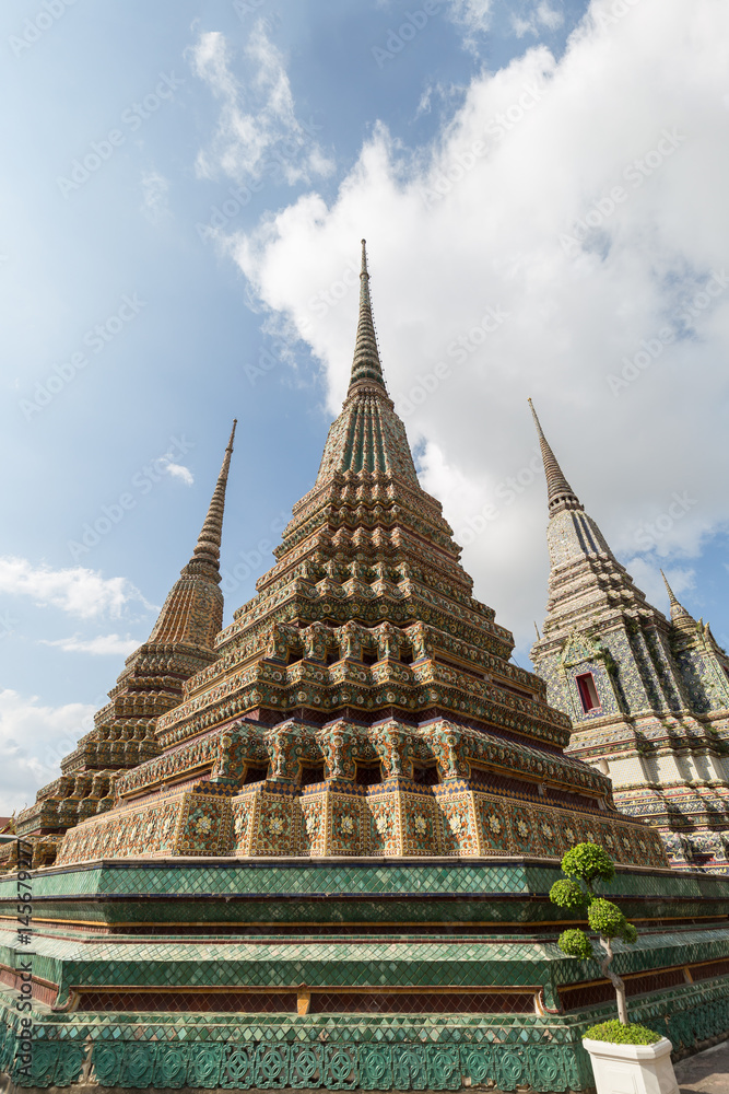 Several ornate chedis at the Wat Pho (Po) temple complex in Bangkok, Thailand, viewed from the front.