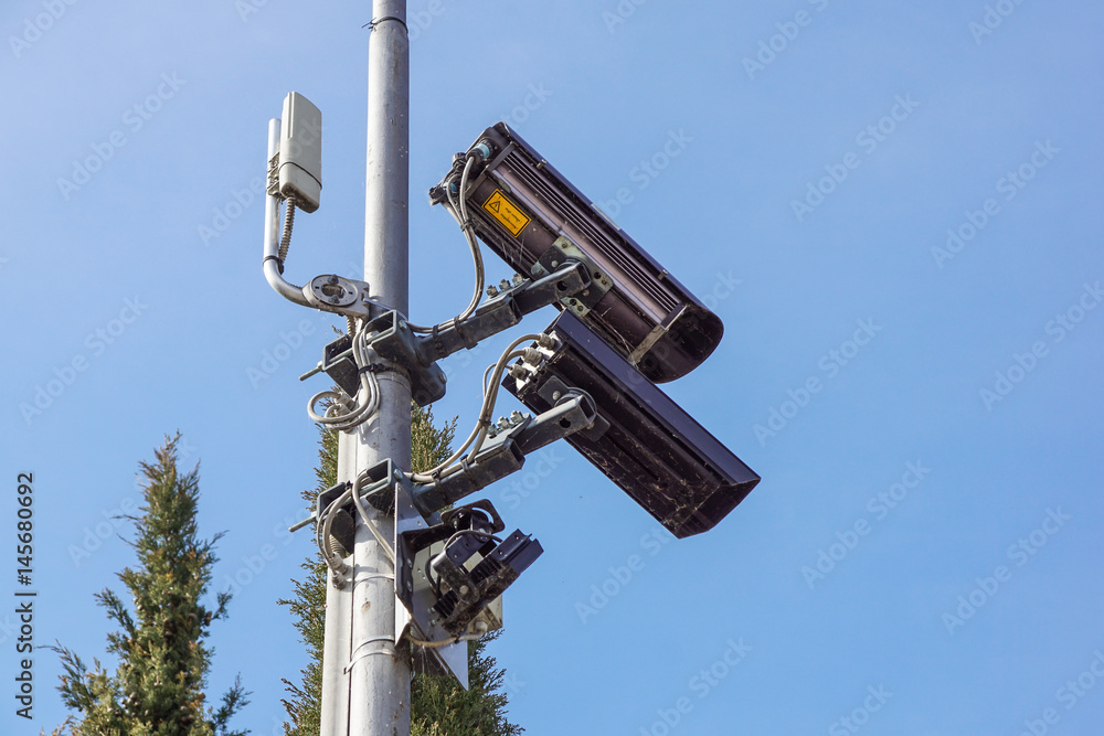 CCTV security camera and surveillance on a pole against the backdrop of blue sky CCTV security camera and surveillance on a pole against the backdrop of blue sky