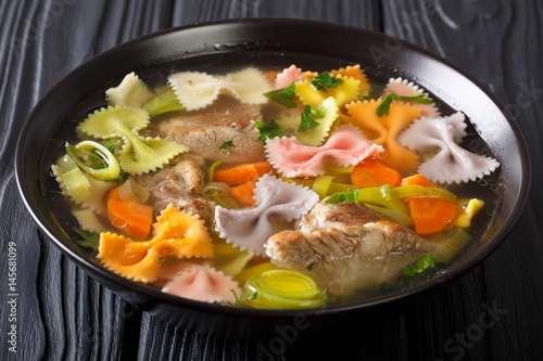 Hearty meat soup, with colored farfalle pasta and vegetables close-up. horizontal