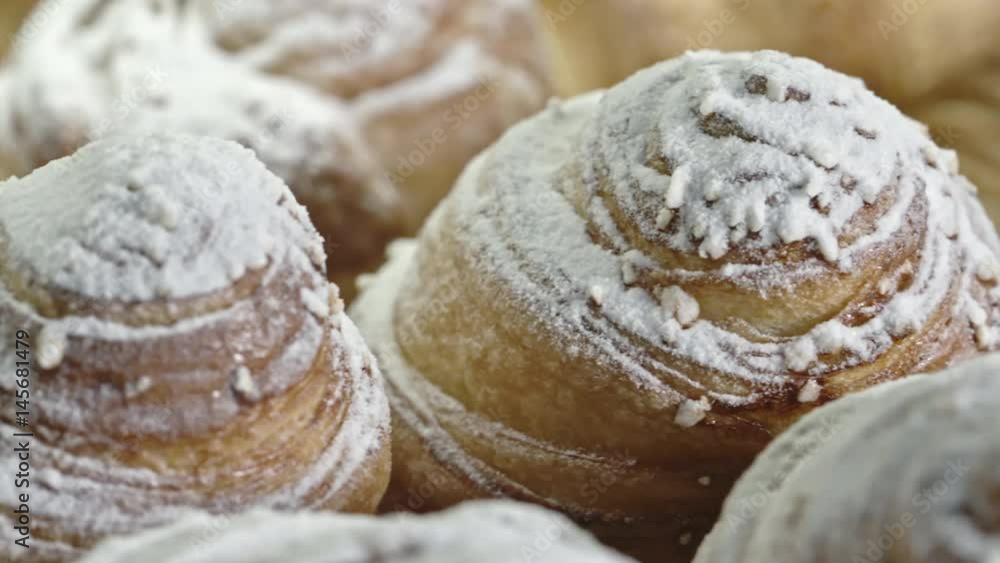 Tracking of lots of freshly baked delicious flaky buns iced with powdered sugar Tracking of lots of freshly baked delicious flaky buns iced with powdered sugar