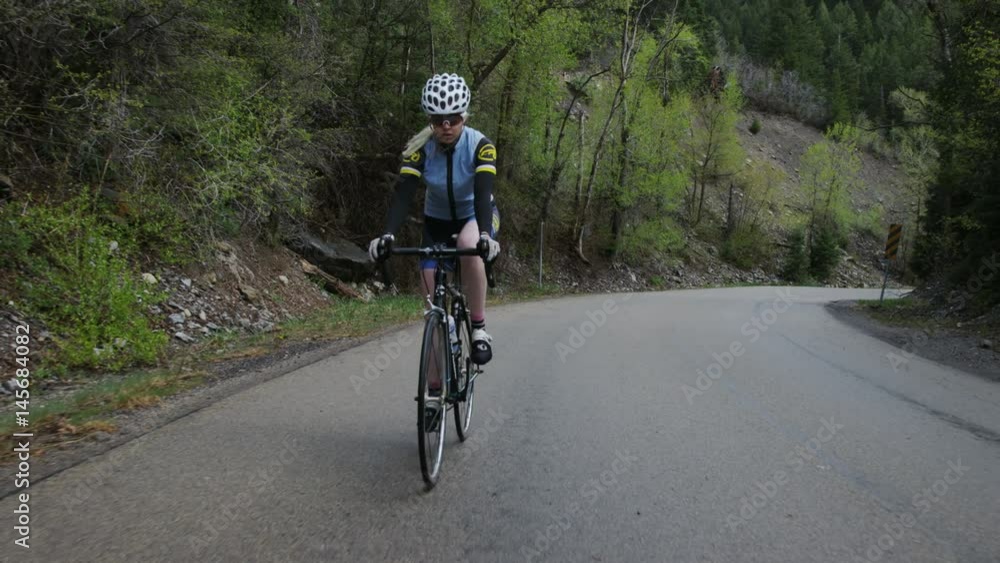 Woman road biking through mountains Woman road biking through mountains