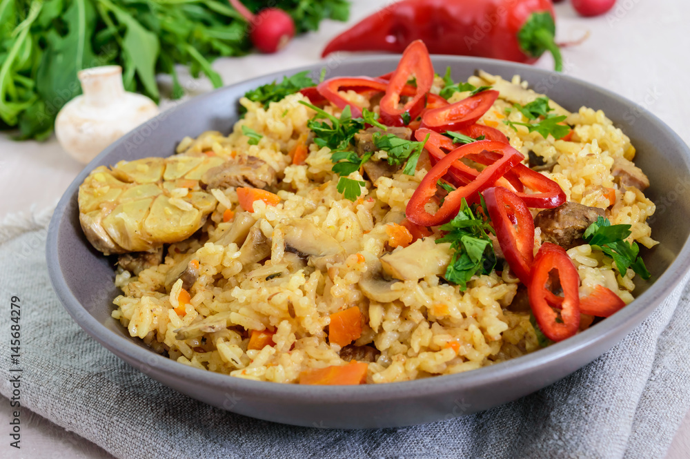 A traditional Asian dish - pilaf with meat, mushrooms and pepper capi in a bowl. A traditional Asian dish - pilaf with meat, mushrooms and pepper capi in a bowl.