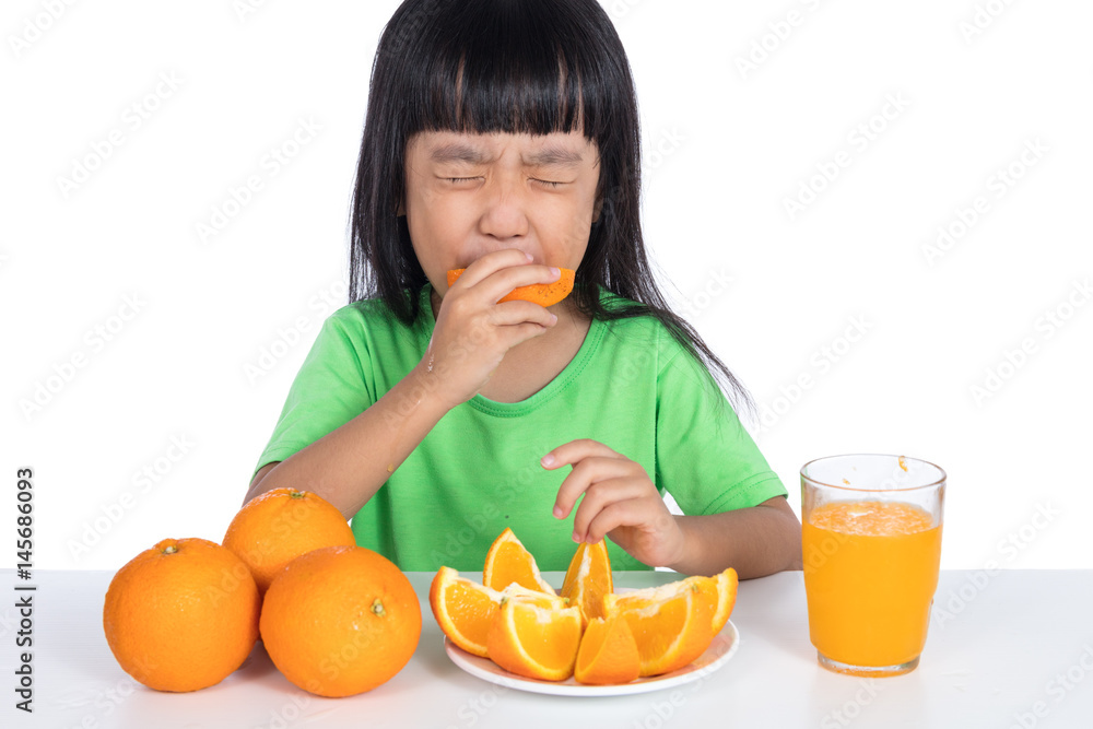 Asian Chinese little girl eating sour orange and making grimace Asian Chinese little girl eating sour orange and making grimace