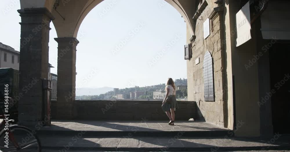 girl sitting on bridge taking in sights while tourists pass by girl sitting on bridge taking in sights while tourists pass by