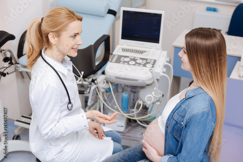 Cuadro en lienzo Positive obstetrician enjoying conversation with pregnant patient at work