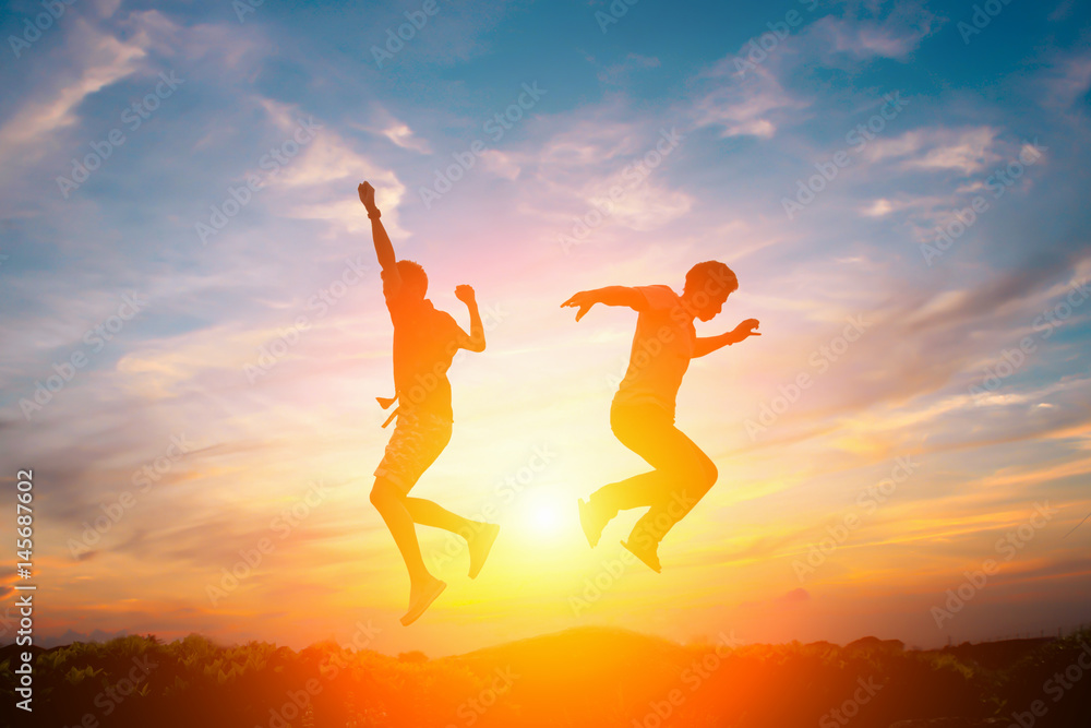 Silhouette of happy people jumping in sunset.