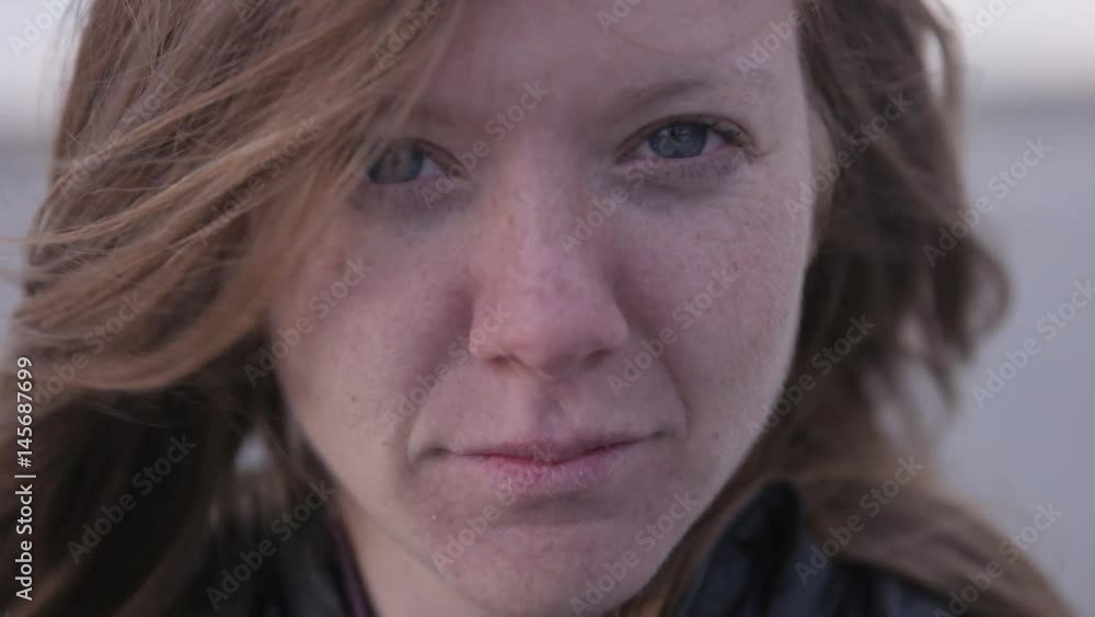 red headed woman staring into camera while wind blows her hair red headed woman staring into camera while wind blows her hair