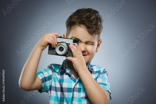 child taking a picture using a retro rangefinder camera isolated grey background photo