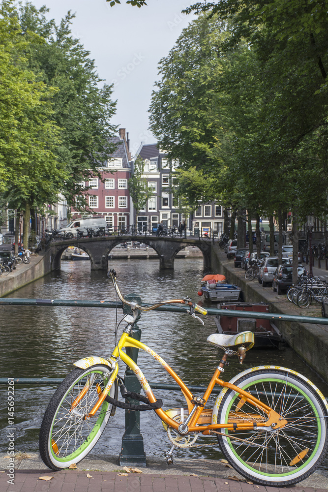 Yellow and green bike near the canal and old bridge in Amsterdam