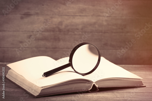 photo of opened notebook and magnifying glass on the wonderful brown wooden background