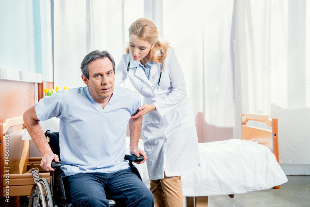 elderly man sitting in wheelchair and doctor helping him in hospital elderly man sitting in wheelchair and doctor helping him in hospital
