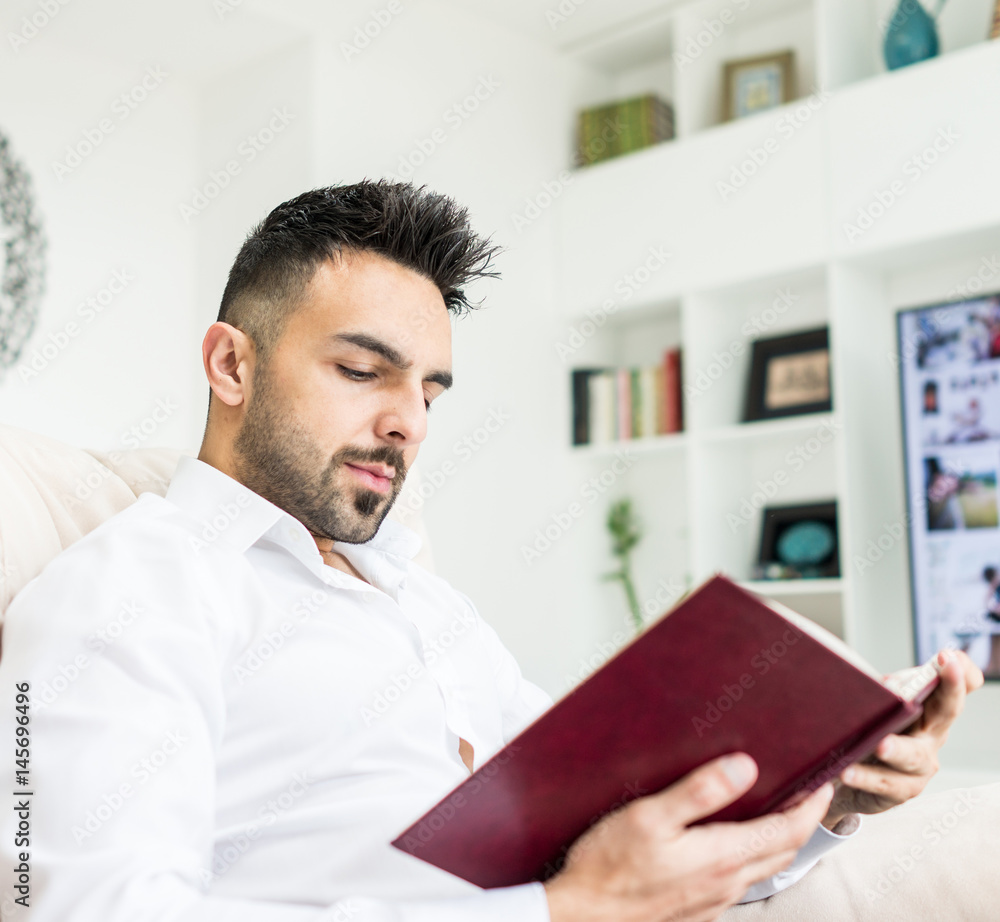 Young confident man reading book at modern home Young confident man reading book at modern home