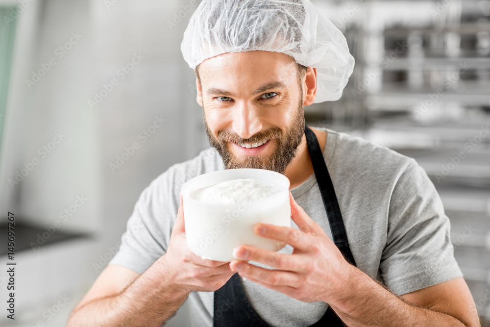 Handsome man in uniform enjoying the process of making cheese at the small producing farm Handsome man in uniform enjoying the process of making cheese at the small producing farm