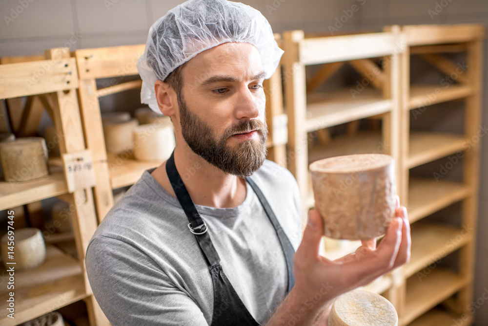 Handsome cheese maker checking the aging process of the goat cheese