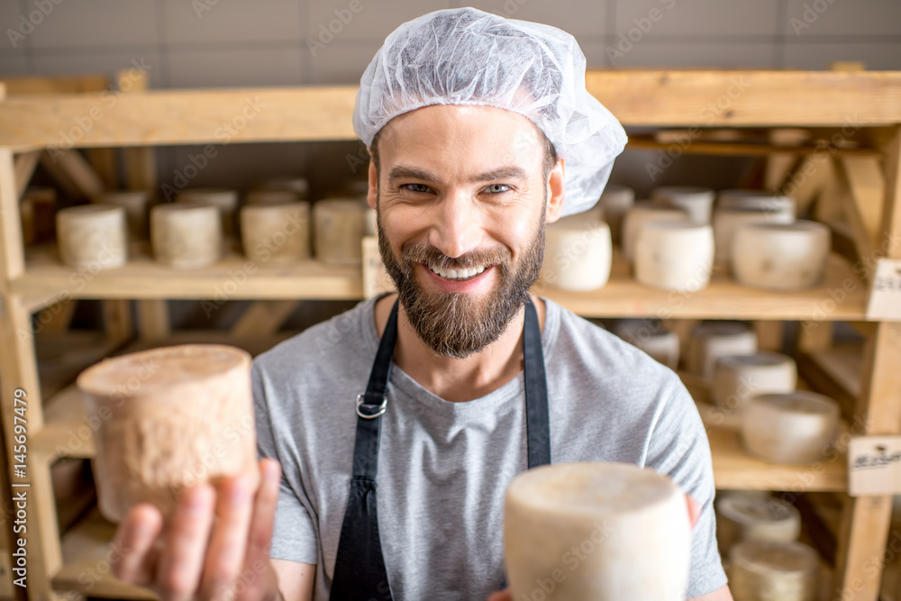 Handsome cheese maker checking the aging process of the goat cheese