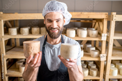 Photos Handsome cheese maker checking the aging process of the goat cheese standing at