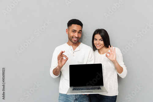 Fotografie Cheerful loving couple showing display of laptop computer