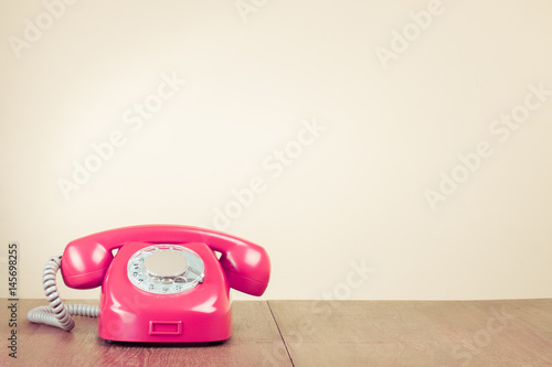 Retro old pink rotary telephone on wooden table