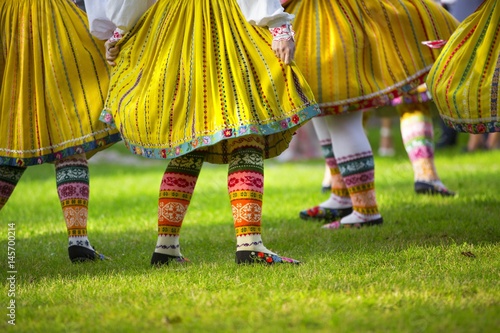 Traditional dancers dancing on the grass with colourful pattern design native shoes and dresses. Folk dance.