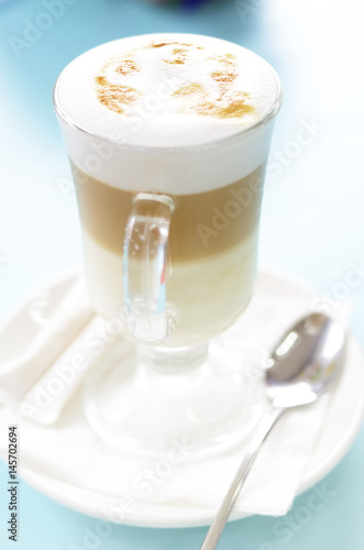 Latte macchiato cup on a blue table. Soft selective focus picture.