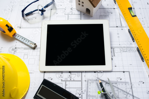 digital tablet with architectural blueprints rolls and tools