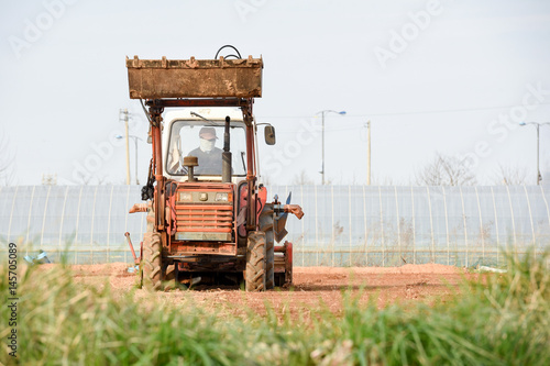 Farmer in tractor preparing land with seedbed cultivator as part of pre seeding activities in early spring season of agricultural works at farmlands.