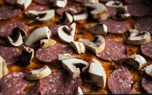 raw pizza with salami and mushrooms