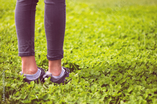 Young girl feet in sport shoes sneakers on green grass on meadow © madiwaso