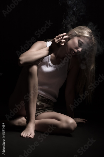 sad smoking blond girl thinker on black background