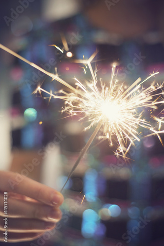 Woman holding sparkler in her hand, celebrating New Year's Eve