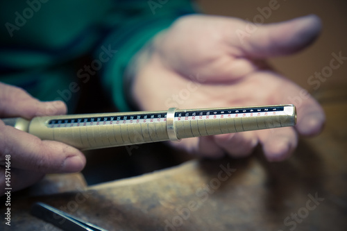 Close up of jeweler using ring mandrel to measure the size of wedding ring