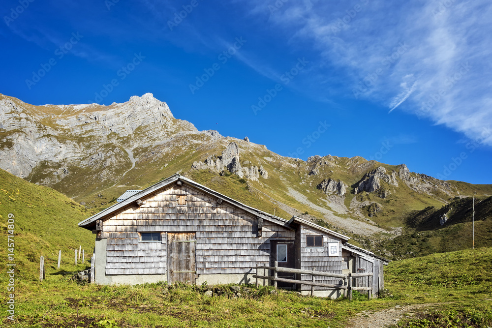 Wooden hut in front of alpine mountain range Wooden hut in front of alpine mountain range