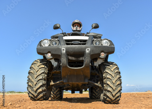 A man riding ATV in sand in a helmet.