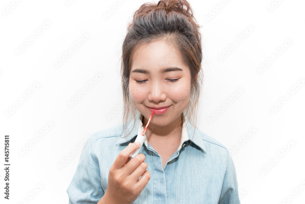 Beautiful young woman close eyes and doing makeup using a lip gloss Beautiful young woman close eyes and doing makeup using a lip gloss