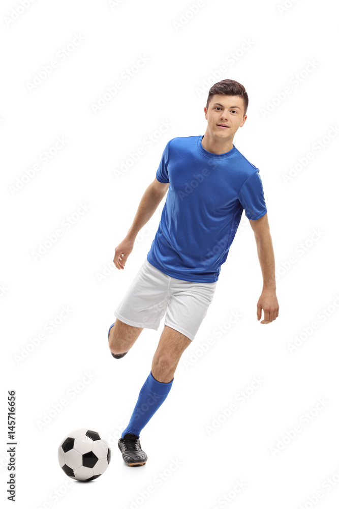 Teenage soccer player kicking a football