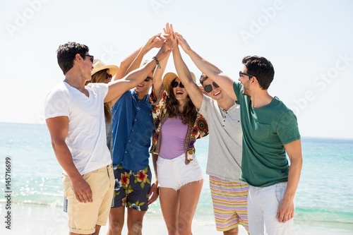 Young friends giving high five while standing at beach