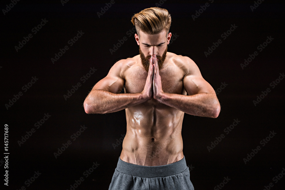 Man in yoga pose with namaste gesture in relaxation yoga classroom isolated on black Man in yoga pose with namaste gesture in relaxation yoga classroom isolated on black